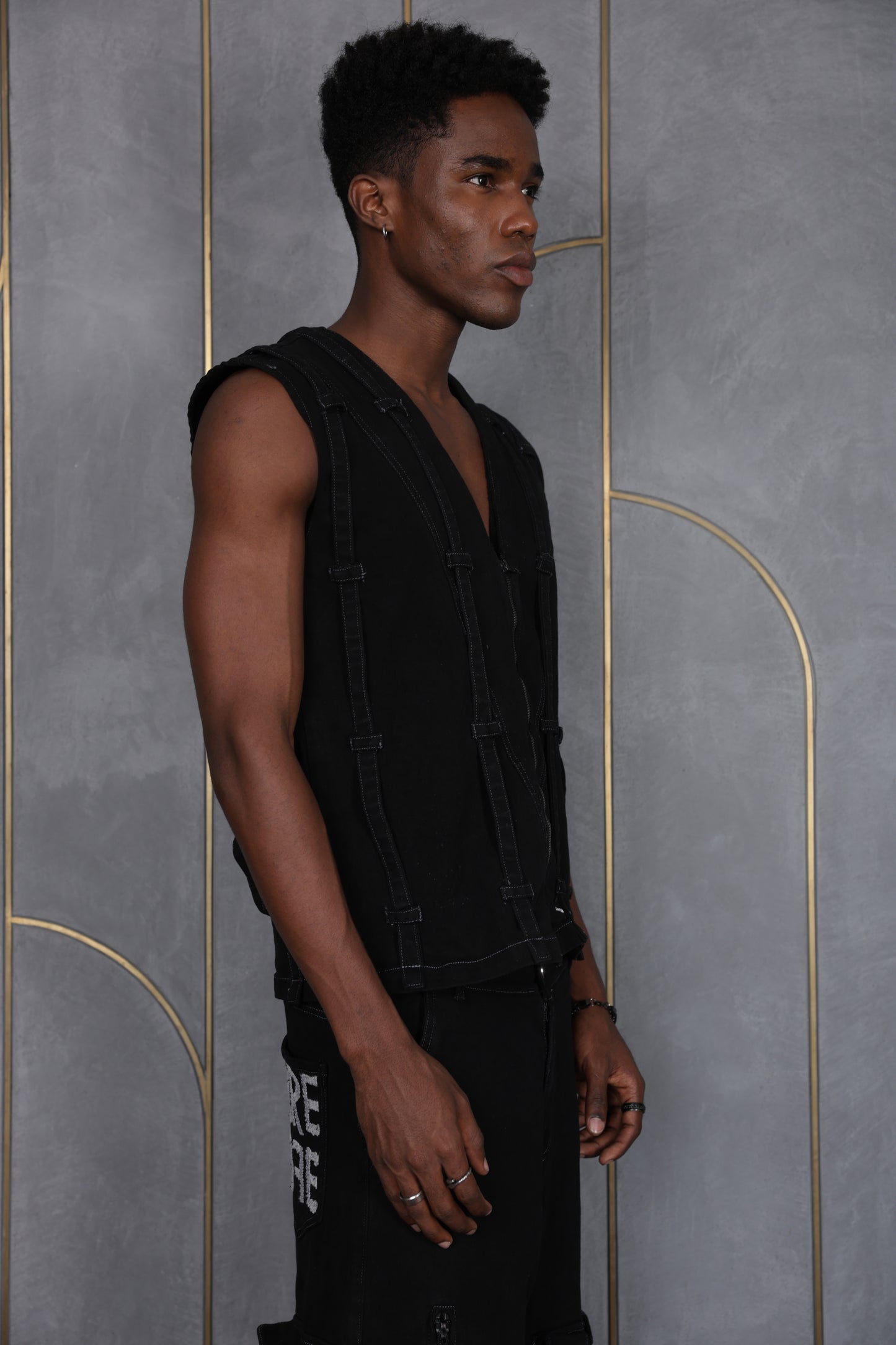 Person wearing ORE OFE's blackout vest and standing in front of a grey wall on a textured rug