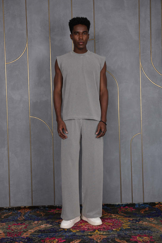 Person wearing ORE OFE's grey waffle tank & bottom standing in front of a grey wall on a textured rug
