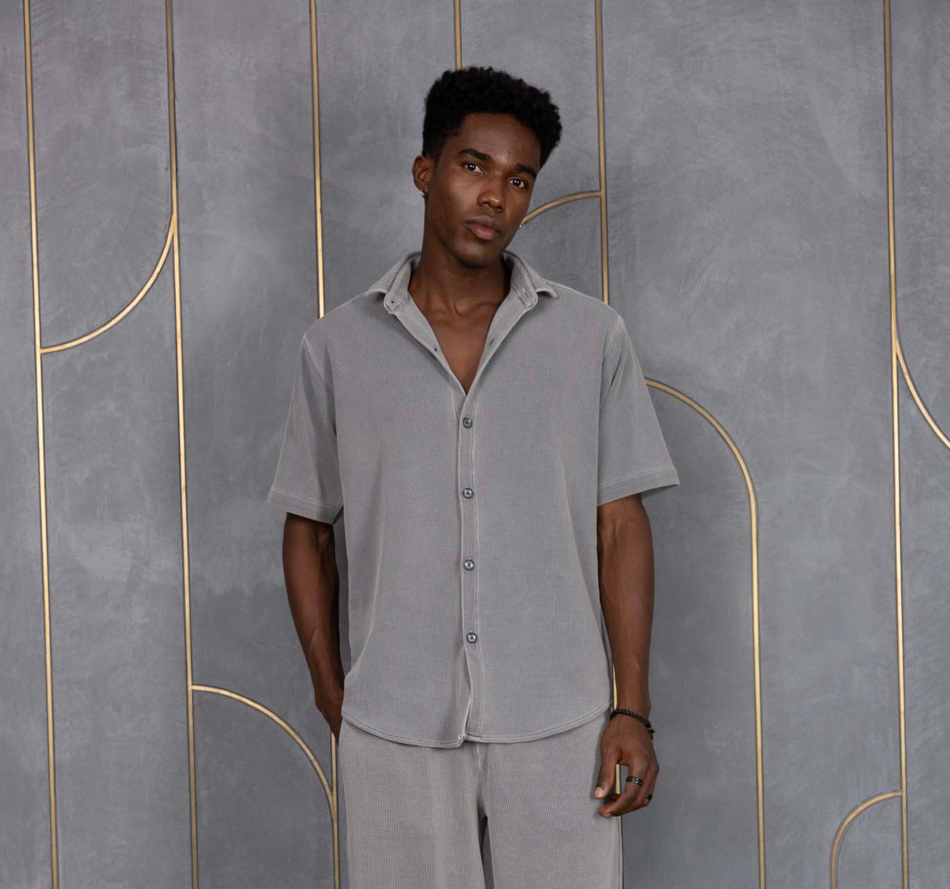 Person wearing ORE OFE's waffle shirt & bottom standing in front of a grey wall on a textured rug