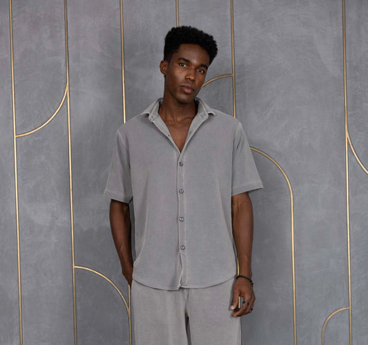 Person wearing ORE OFE's waffle shirt & bottom standing in front of a grey wall on a textured rug