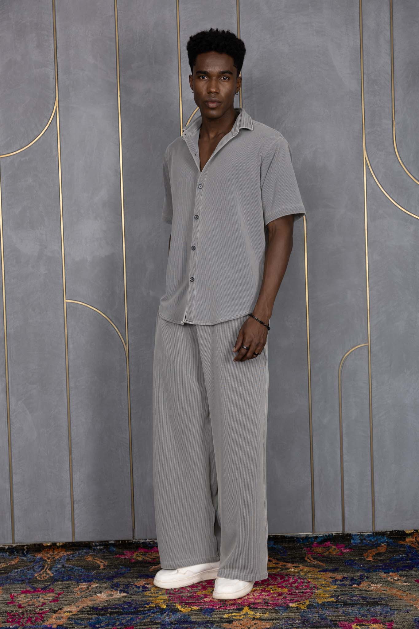 Person wearing ORE OFE's waffle shirt & bottom standing in front of a grey wall on a textured rug