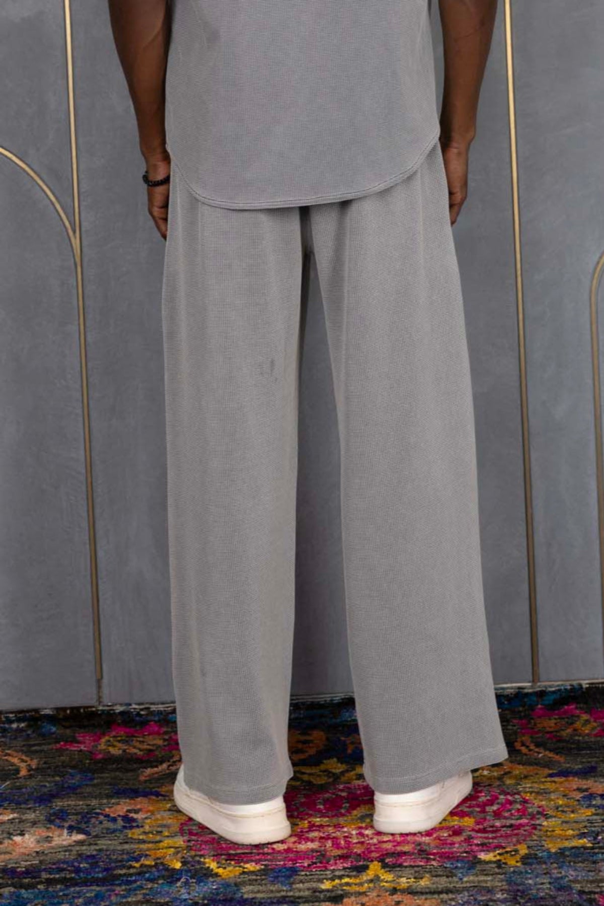 Person wearing ORE OFE's waffle shirt & bottom standing in front of a grey wall on a textured rug