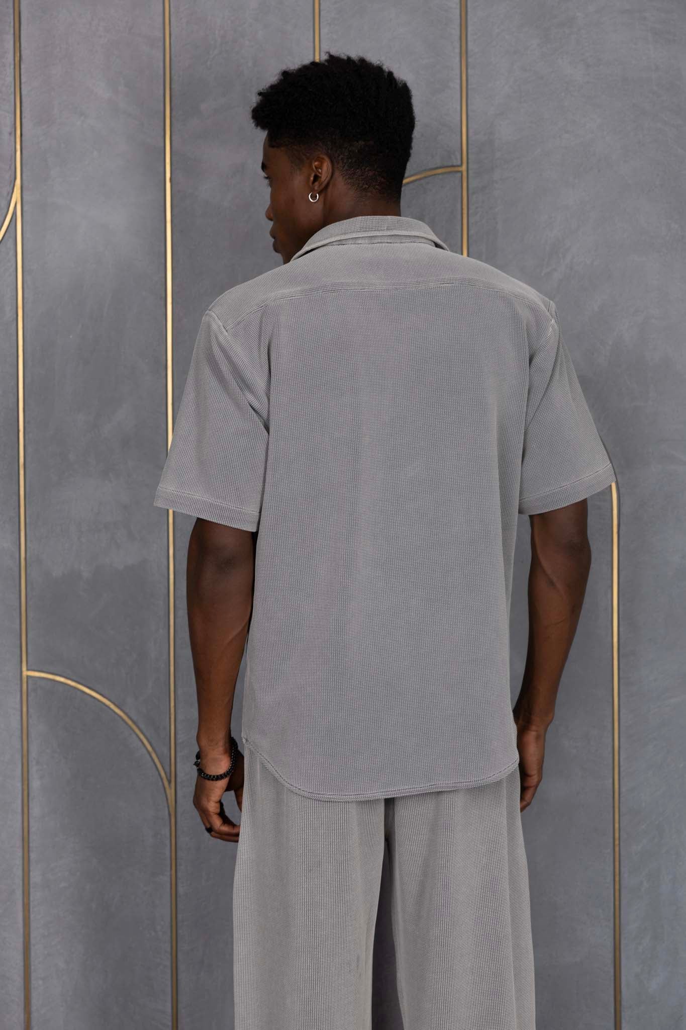 Person wearing ORE OFE's waffle shirt & bottom standing in front of a grey wall on a textured rug