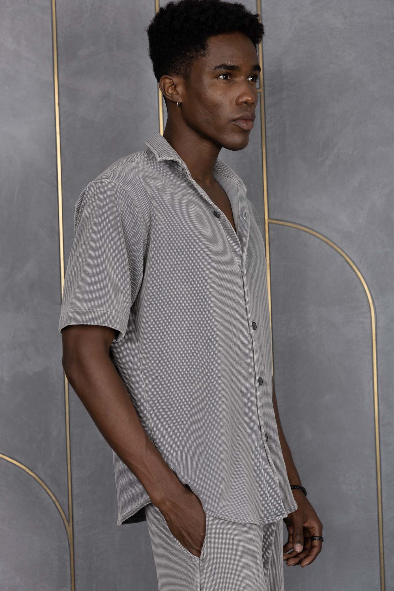 Person wearing ORE OFE's waffle shirt & bottom standing in front of a grey wall on a textured rug