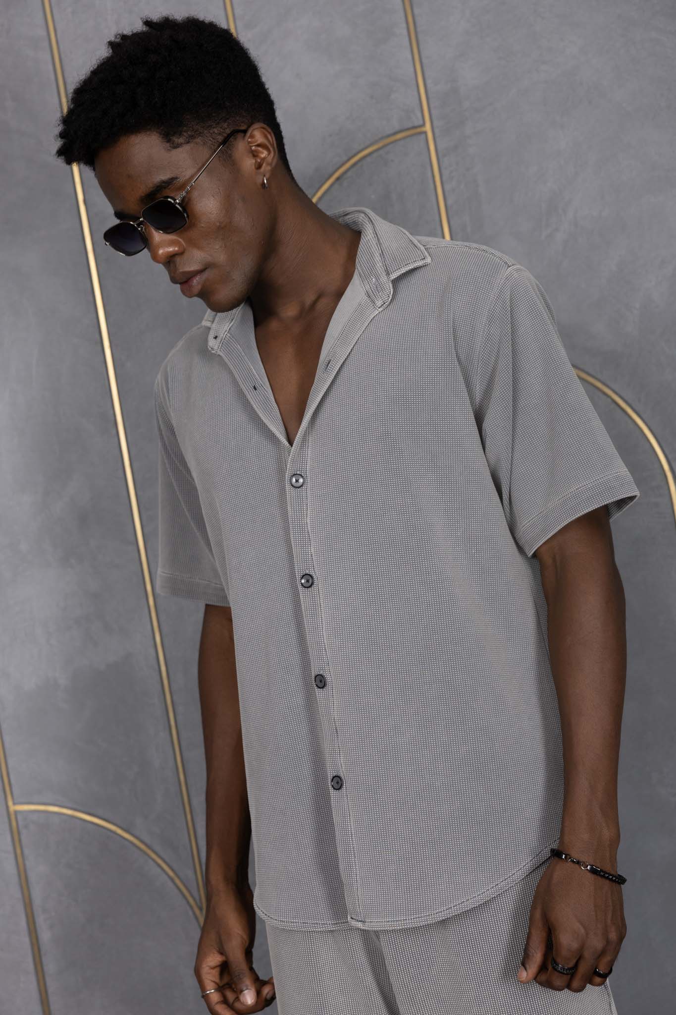 Person wearing ORE OFE's waffle shirt & bottom standing in front of a grey wall on a textured rug