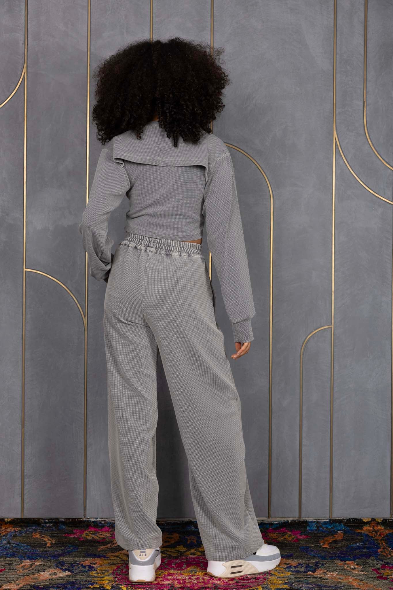 Woman wearing ORE OFE's grey waffle tank & bottom standing in front of a grey wall on a textured rug