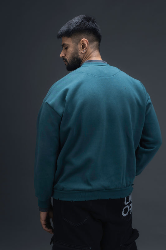 Man wearing ORE OFEs green contrast sweatshirt with the logo on the centre of the chest standing against a grey background
