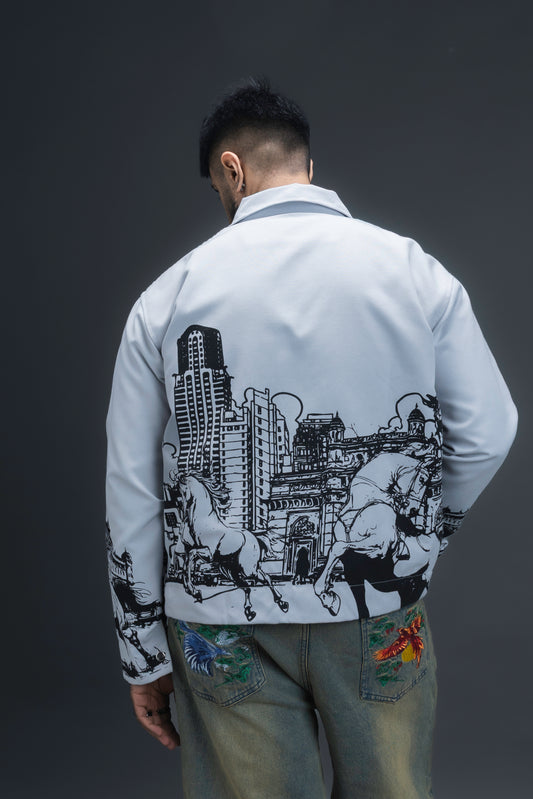 Person wearing ORE OFE's light grey jacket that has the Bombay skyline with horses printed on it standing against a dark grey background