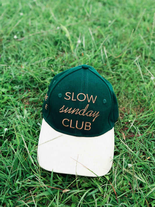 Green and white ORE OFEbaseball cap with 'Slow Sunday Club' text on grass