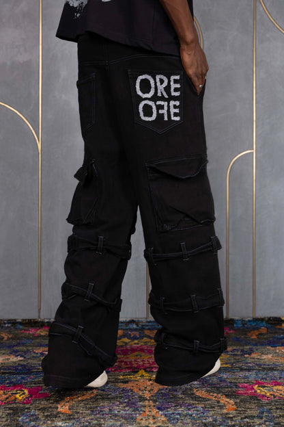 Person wearing ORE OFE's blackout t-shirt & denim and standing in front of a grey wall on a textured rug