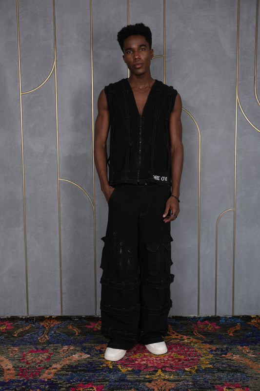Person wearing ORE OFE's blackout vest and standing in front of a grey wall on a textured rug