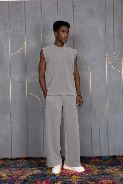 Person wearing ORE OFE's grey waffle tank & bottom standing in front of a grey wall on a textured rug