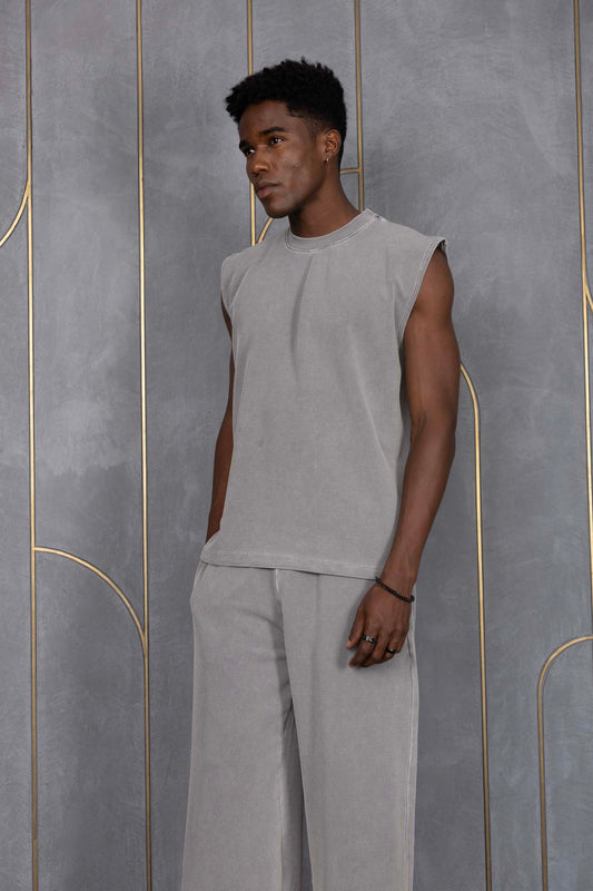 Person wearing ORE OFE's grey waffle tank & bottom standing in front of a grey wall on a textured rug