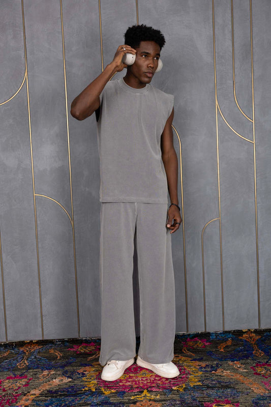 Person wearing ORE OFE's grey waffle tank & bottom standing in front of a grey wall on a textured rug