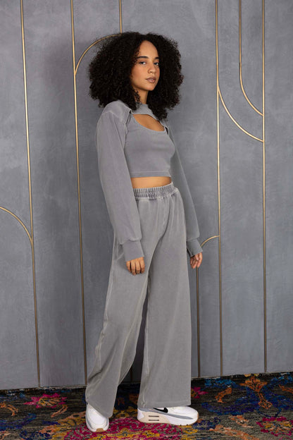 Woman wearing ORE OFE's grey waffle tank & bottom standing in front of a grey wall on a textured rug