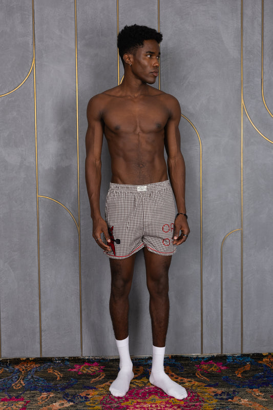 Model wearing white and black small checkered ORE OFE boxers with a dog lifting weights printed with ORE OFE logo