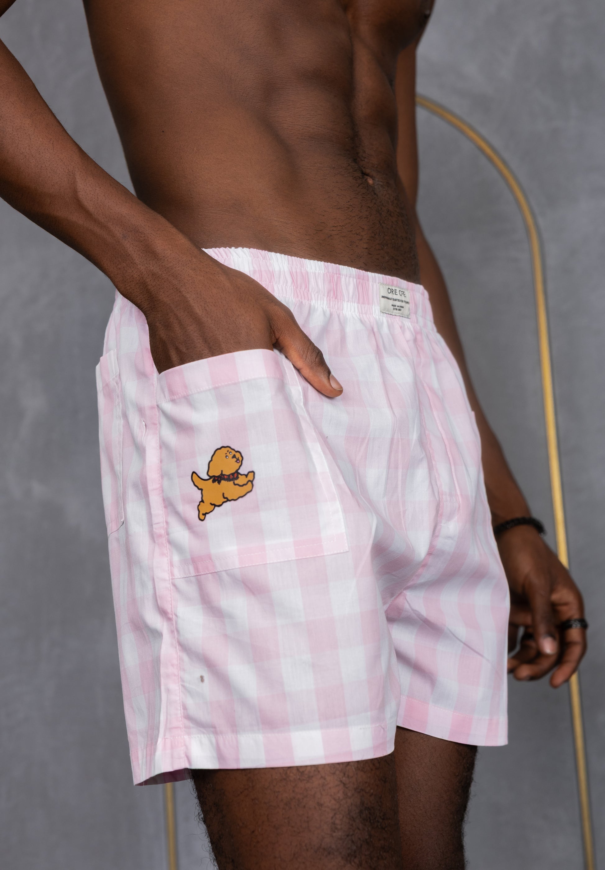 Model wearing pink checkered boxers with a side pocket and a dog design