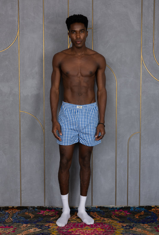 Model wearing blue checkered ORE OFE boxers with pawrty printed on it