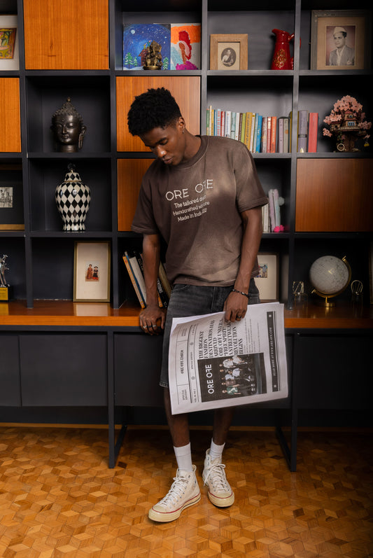 Person holding a newspaper in front of a bookshelf