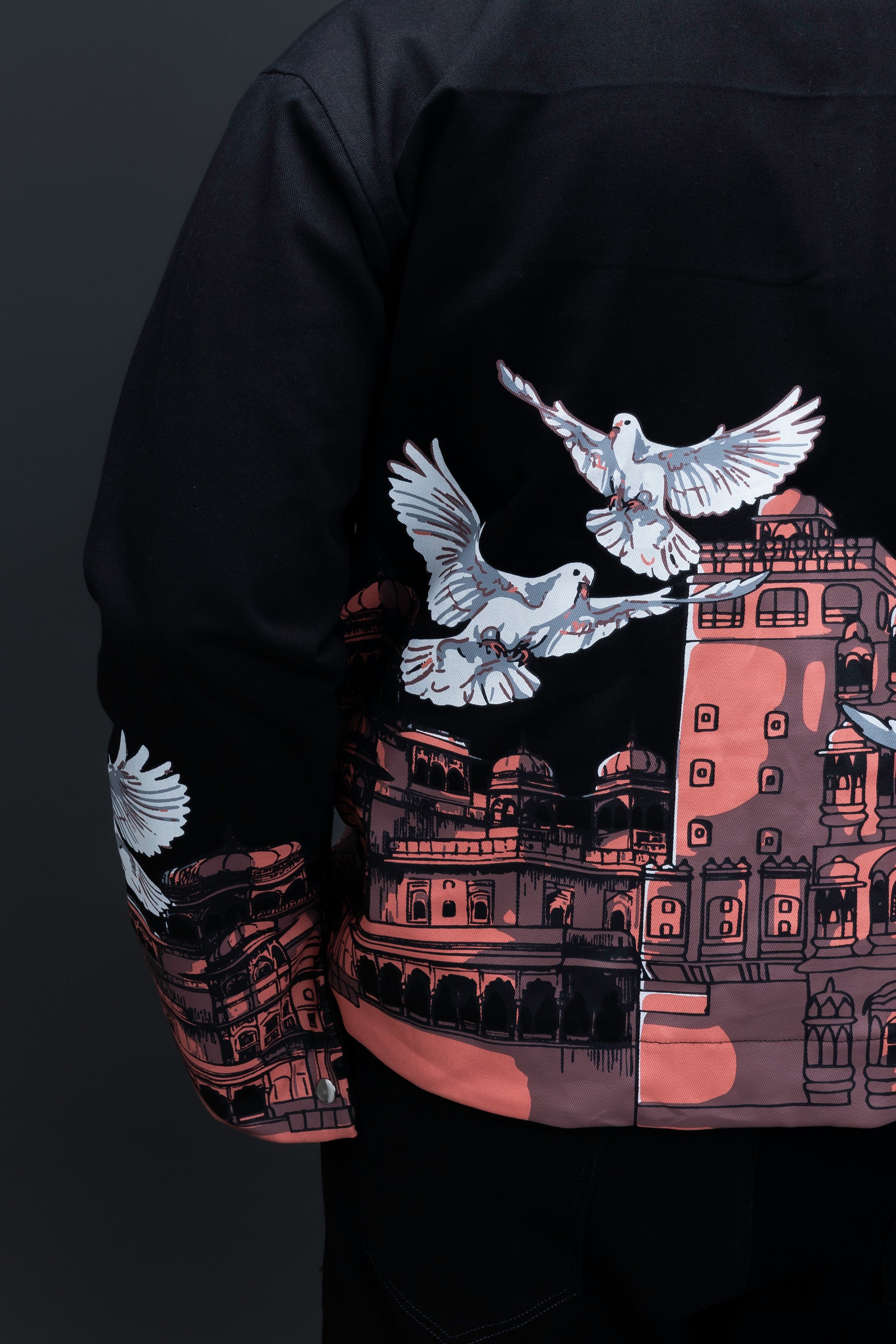 Man wearing ORE OFE's heritage black jacket that is designed on the theme of Hawa mahal standing against a grey background