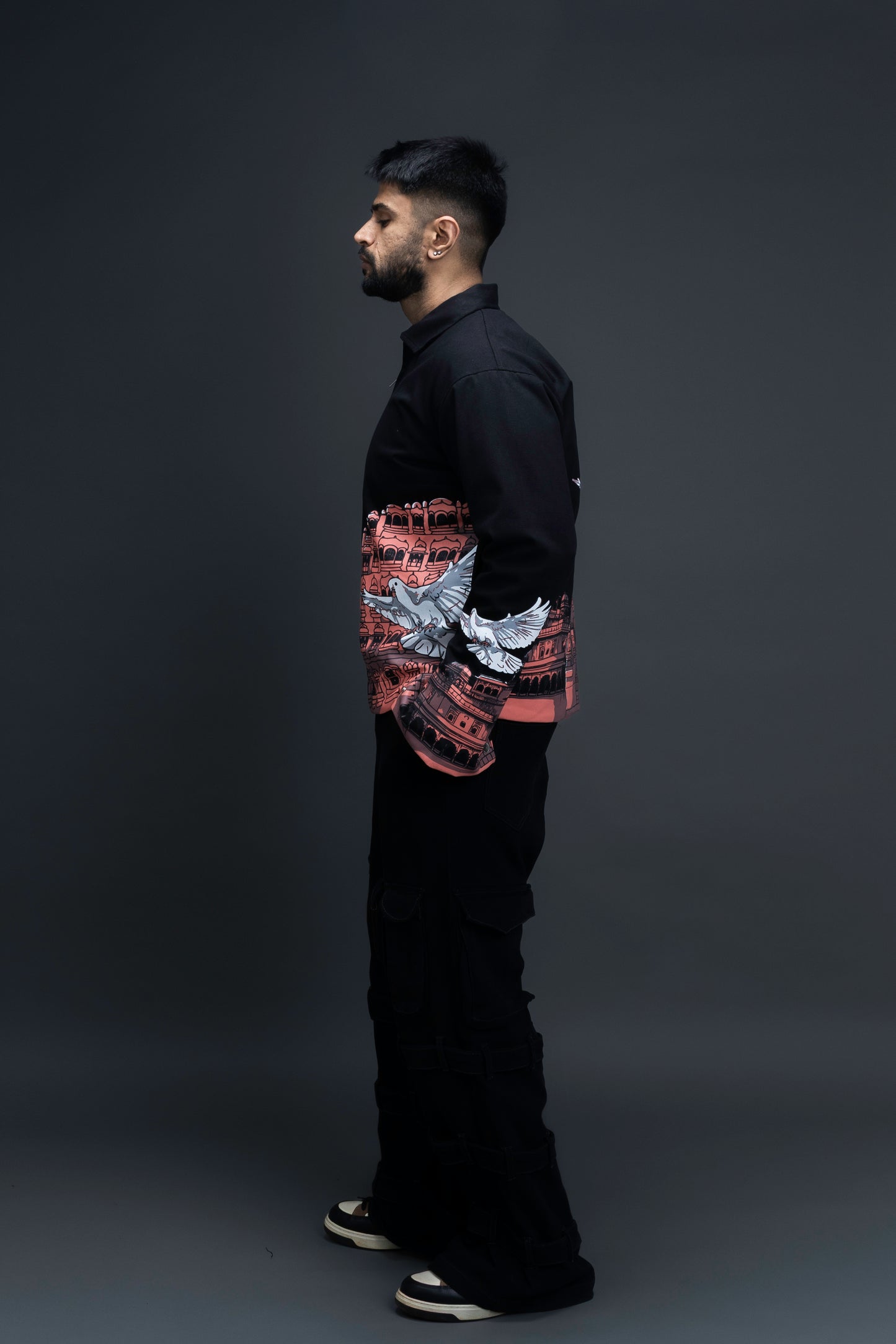 Man wearing ORE OFE's heritage black jacket that is designed on the theme of Hawa mahal standing against a grey background