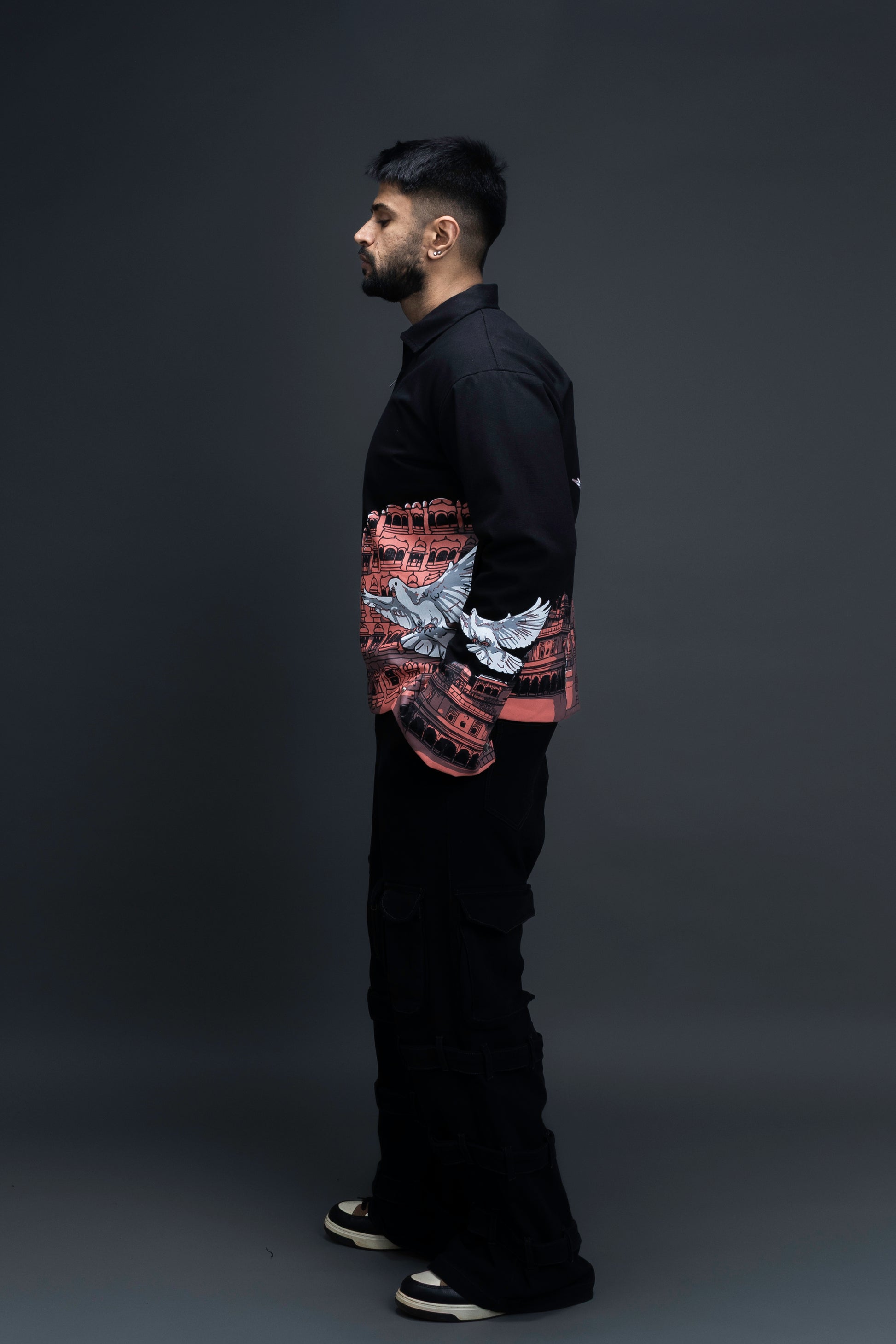 Man wearing ORE OFE's heritage black jacket that is designed on the theme of Hawa mahal standing against a grey background