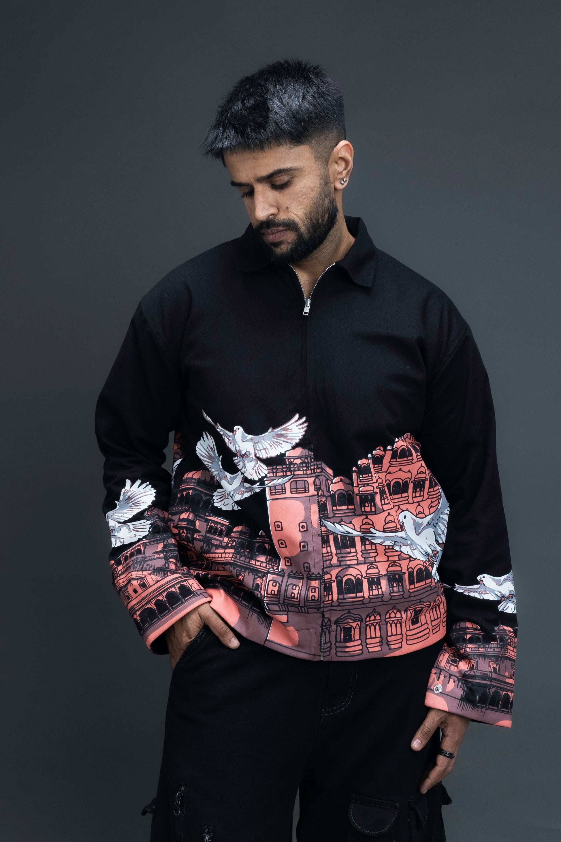 Man wearing ORE OFE's heritage black jacket that is designed on the theme of Hawa mahal standing against a grey background