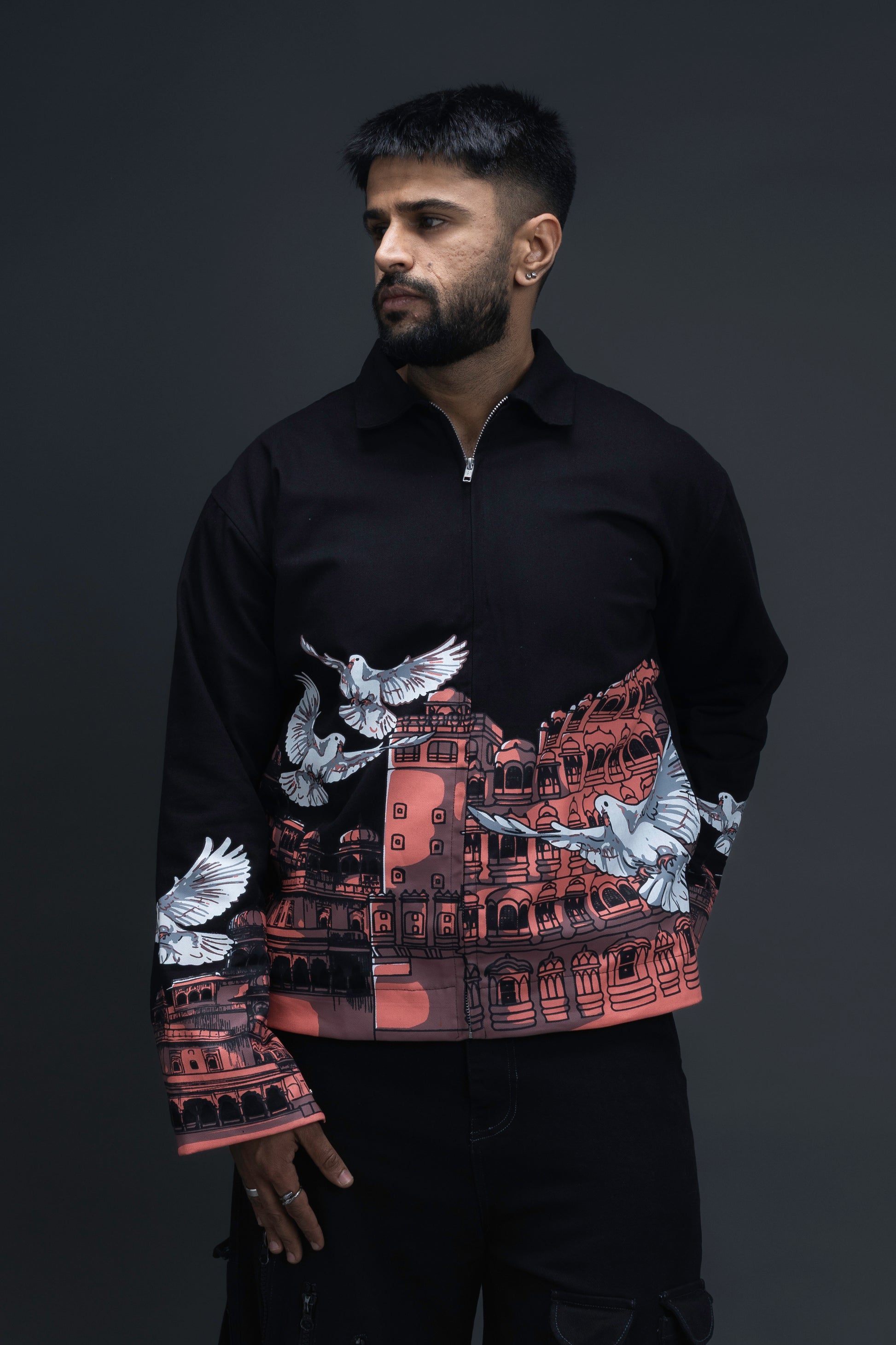 Man wearing ORE OFE's heritage black jacket that is designed on the theme of Hawa mahal standing against a grey background