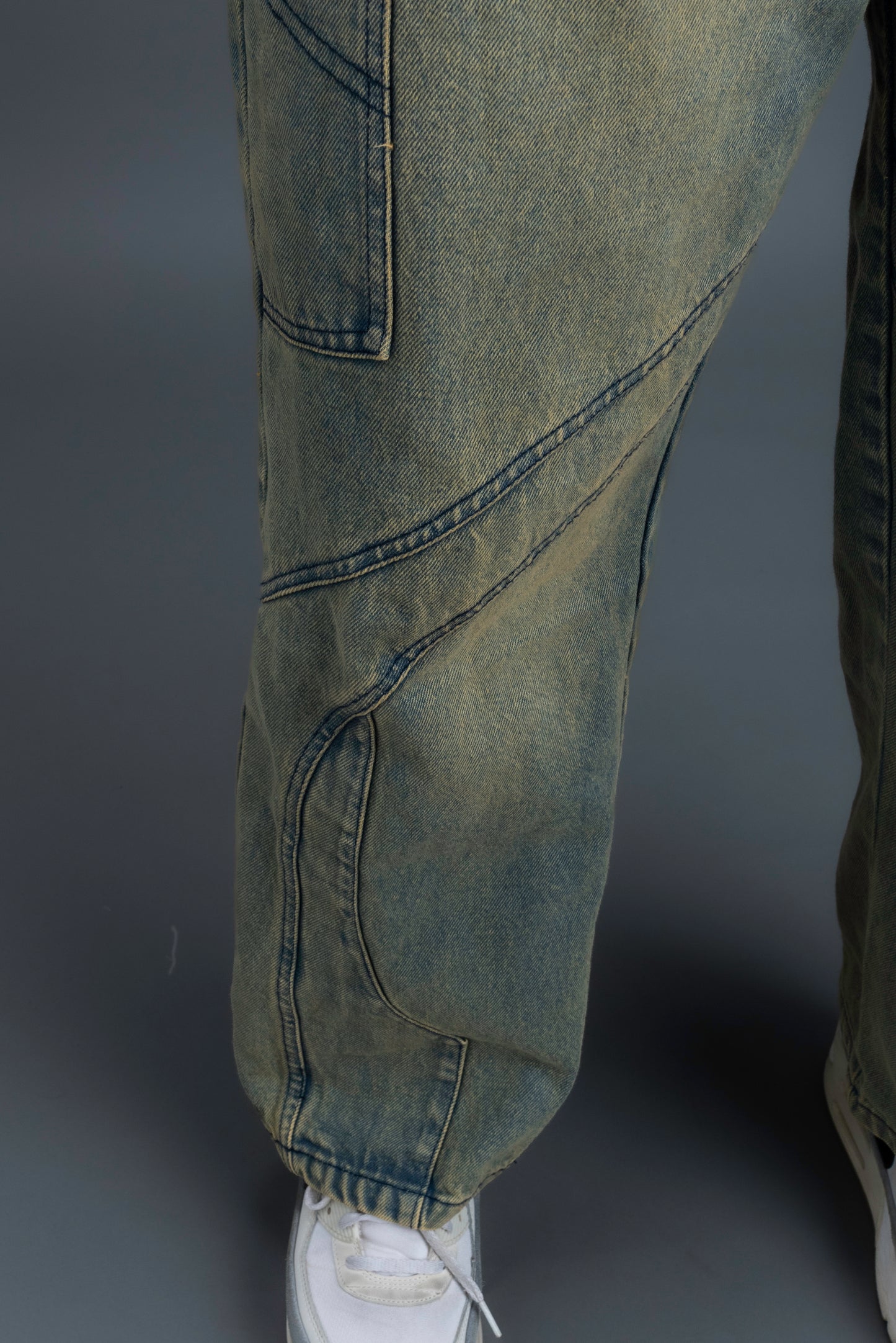 Person wearing ORE OFE's Vintage washed denim that has a pheonix embroided on the back pocket standing against a grey background