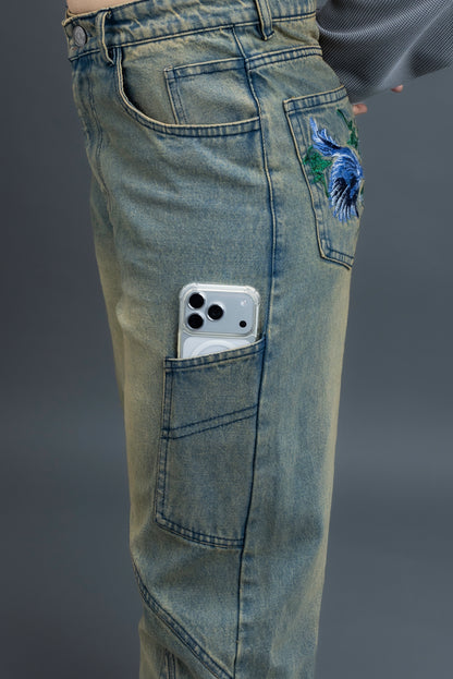 Person wearing ORE OFE's Vintage washed denim that has a pheonix embroided on the back pocket standing against a grey background