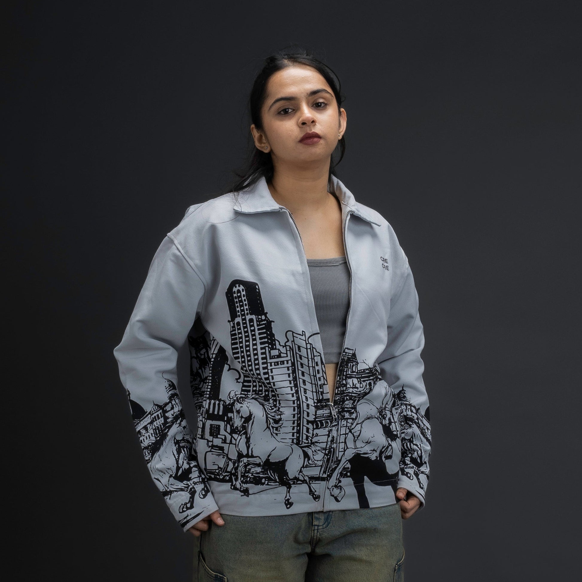Woman wearing Jacket by ORE OFE  capturing the raw energy of Mumbai  standing against a gray background