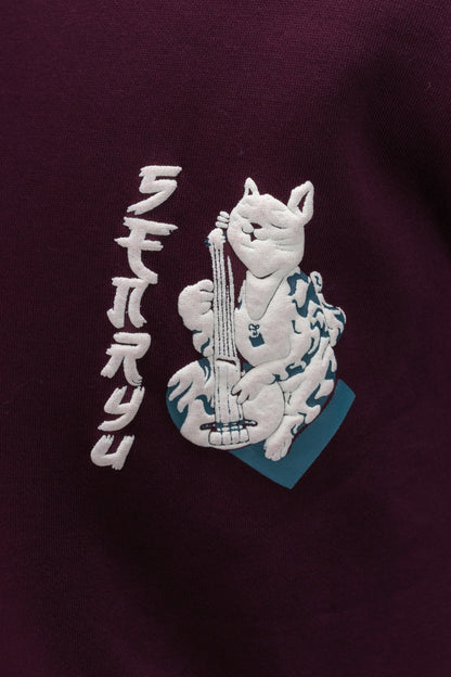 Person wearing a maroon contrast hoodie by ORE OFE with chest & back puff printed design  standaing against  a dark grey background