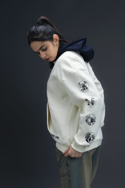 Person wearing a off-white contrast hoodie by ORE OFE with text on the chest that reads GRITTY & design on both sleeves, standing against a black background 