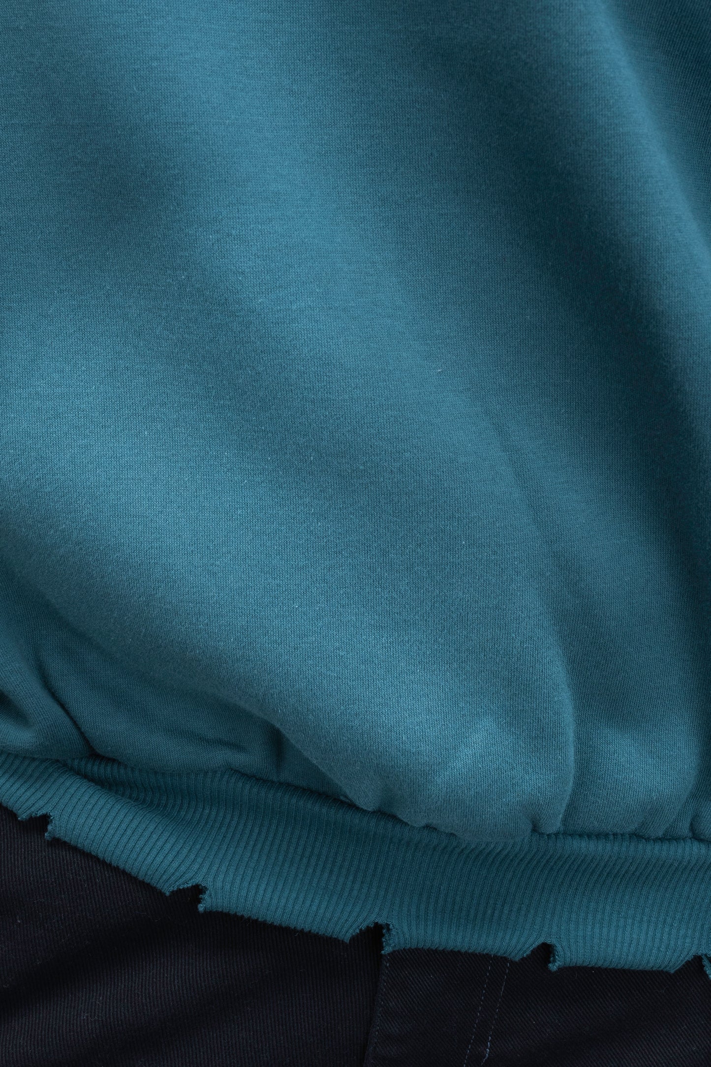 Man wearing ORE OFEs green contrast sweatshirt with the logo on the centre of the chest standing against a grey background