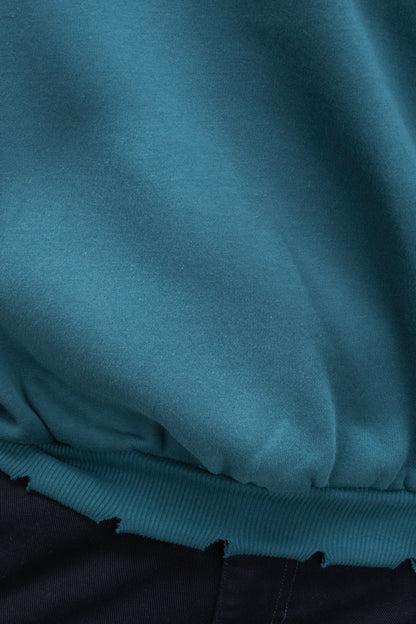 Man wearing ORE OFEs green contrast sweatshirt with the logo on the centre of the chest standing against a grey background