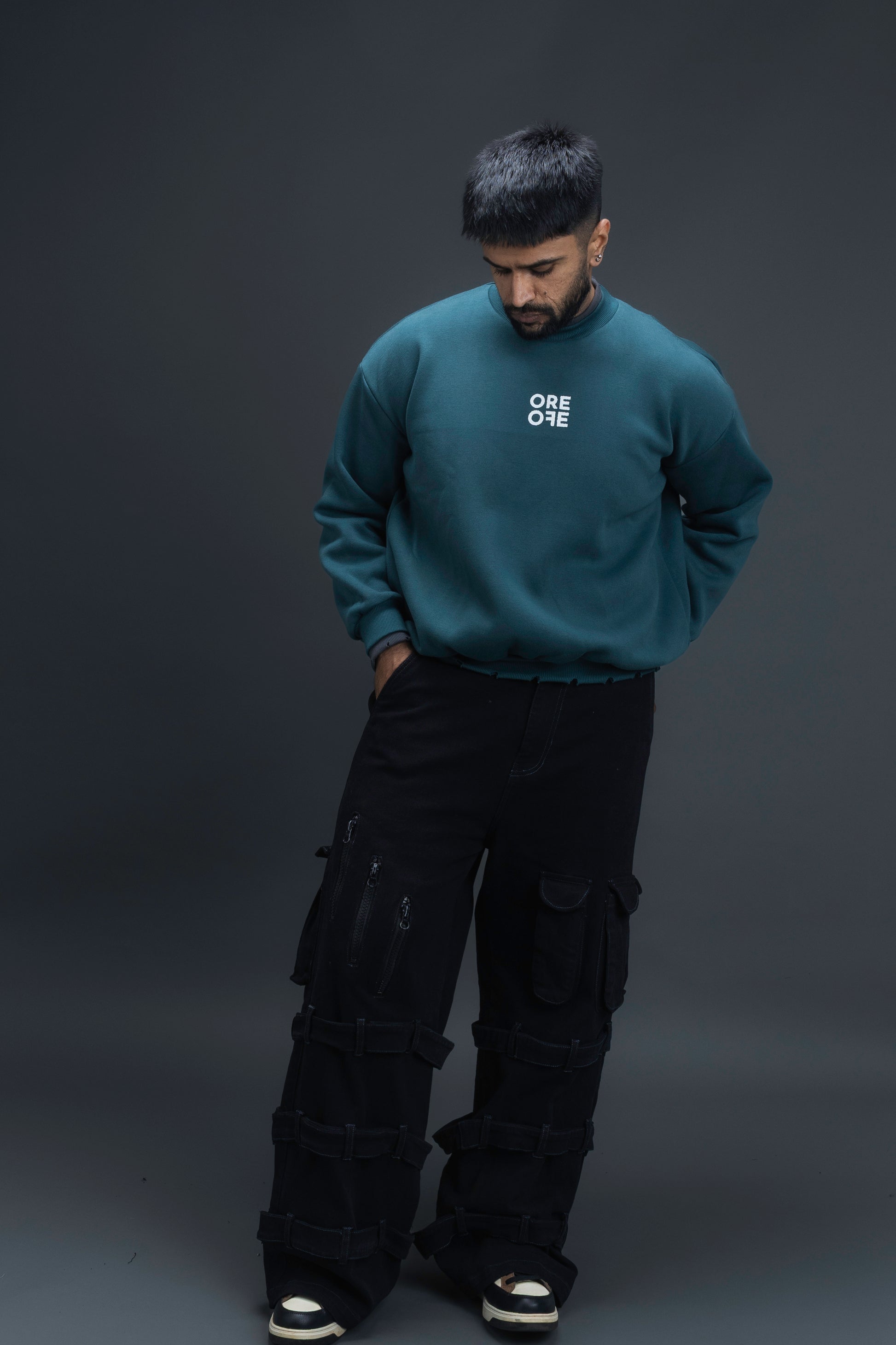 Man wearing ORE OFEs green contrast sweatshirt with the logo on the centre of the chest standing against a grey background