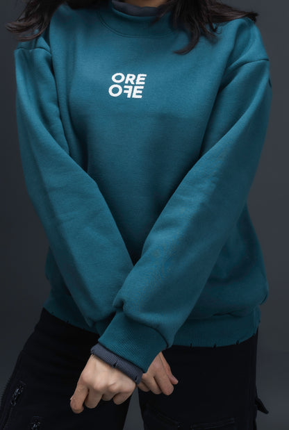 Person wearing a teal sweater with ORE OFE logo on the centre of the chest