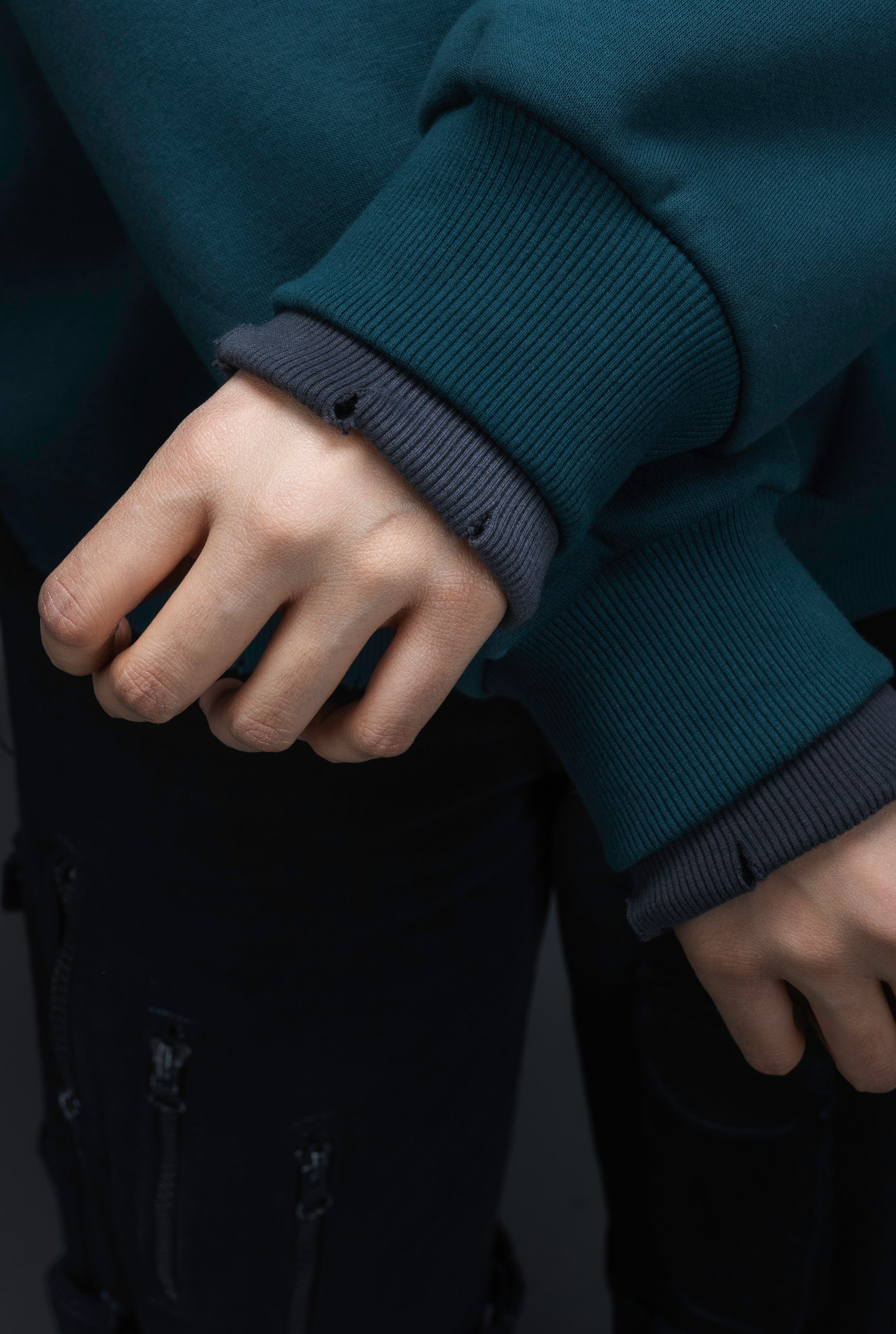 Close-up of a person wearing a teal contrast sweatshirt by ORE OFE that shows the contrast on the wrist