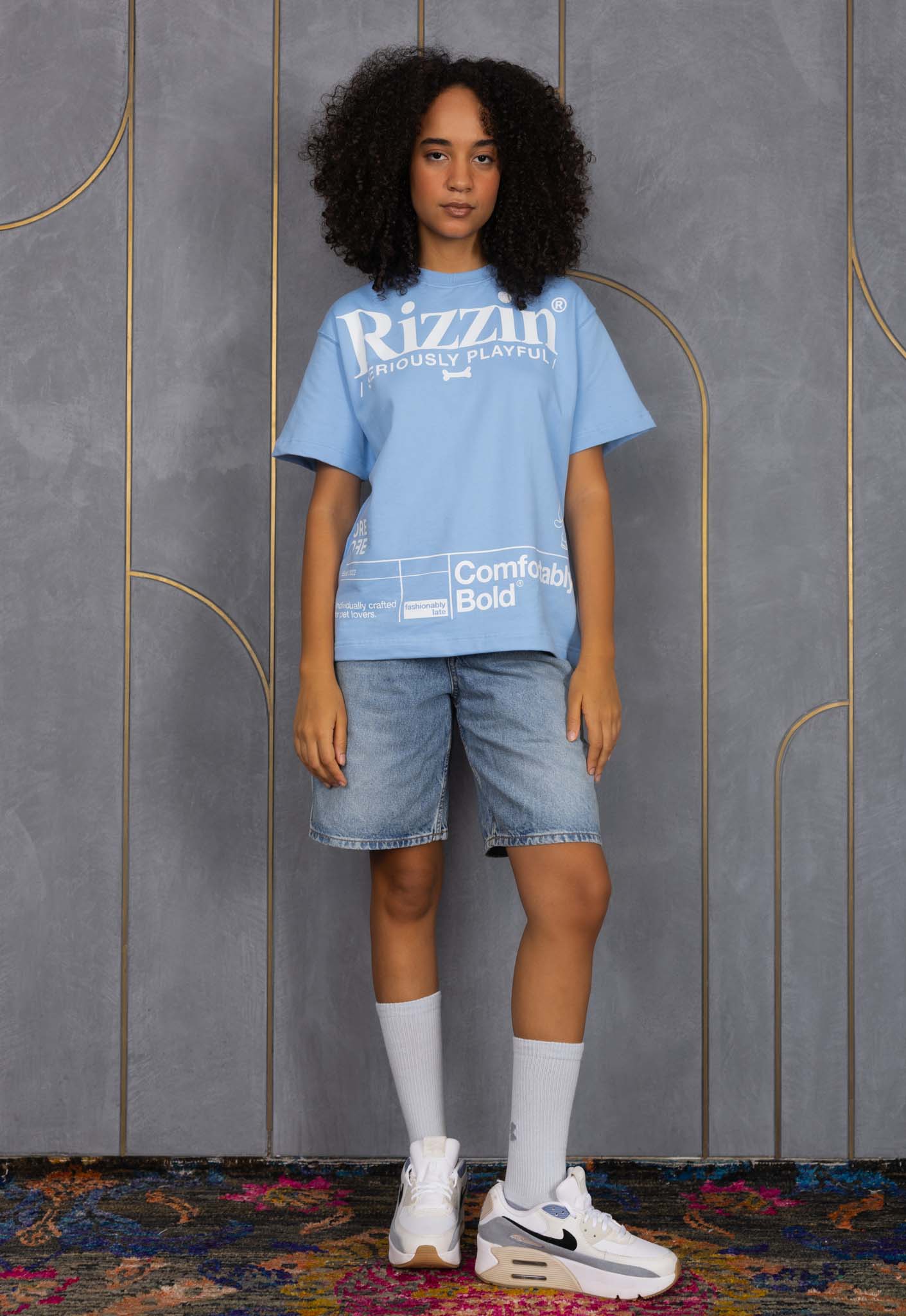 Person wearing a blue t-shirt with visible branding against a gray wall.