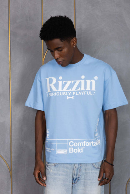 Person wearing a blue 'Rizzin' t-shirt against a gray wall.