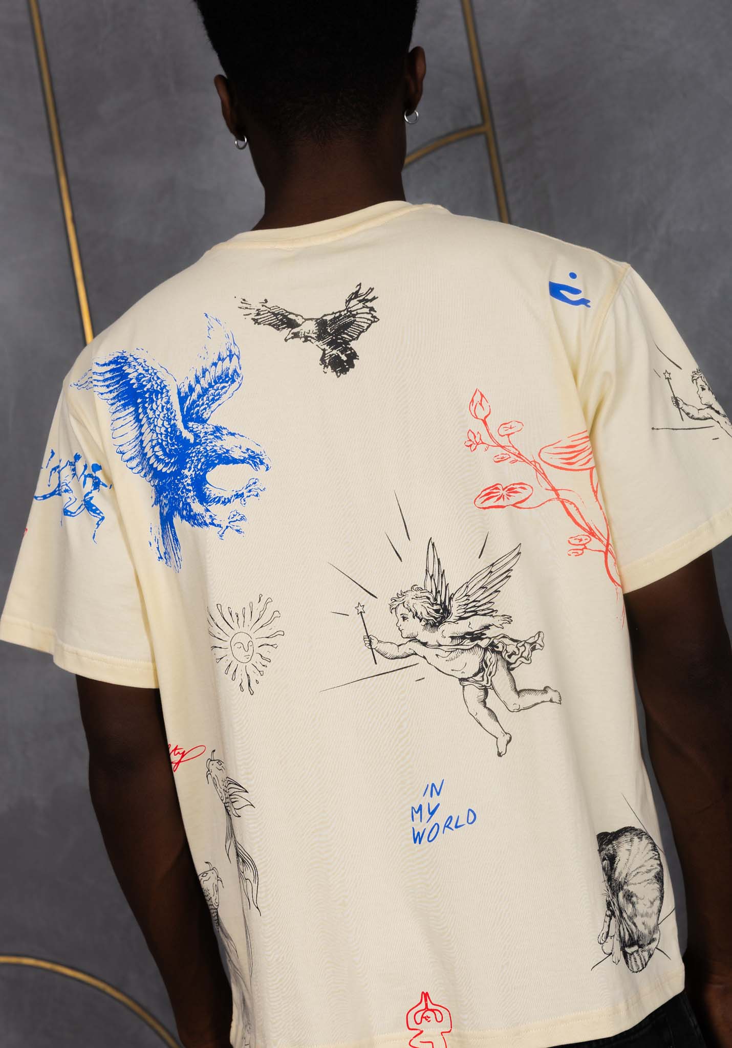 Person wearing a cream-colored t-shirt with colorful graphics on a gray background