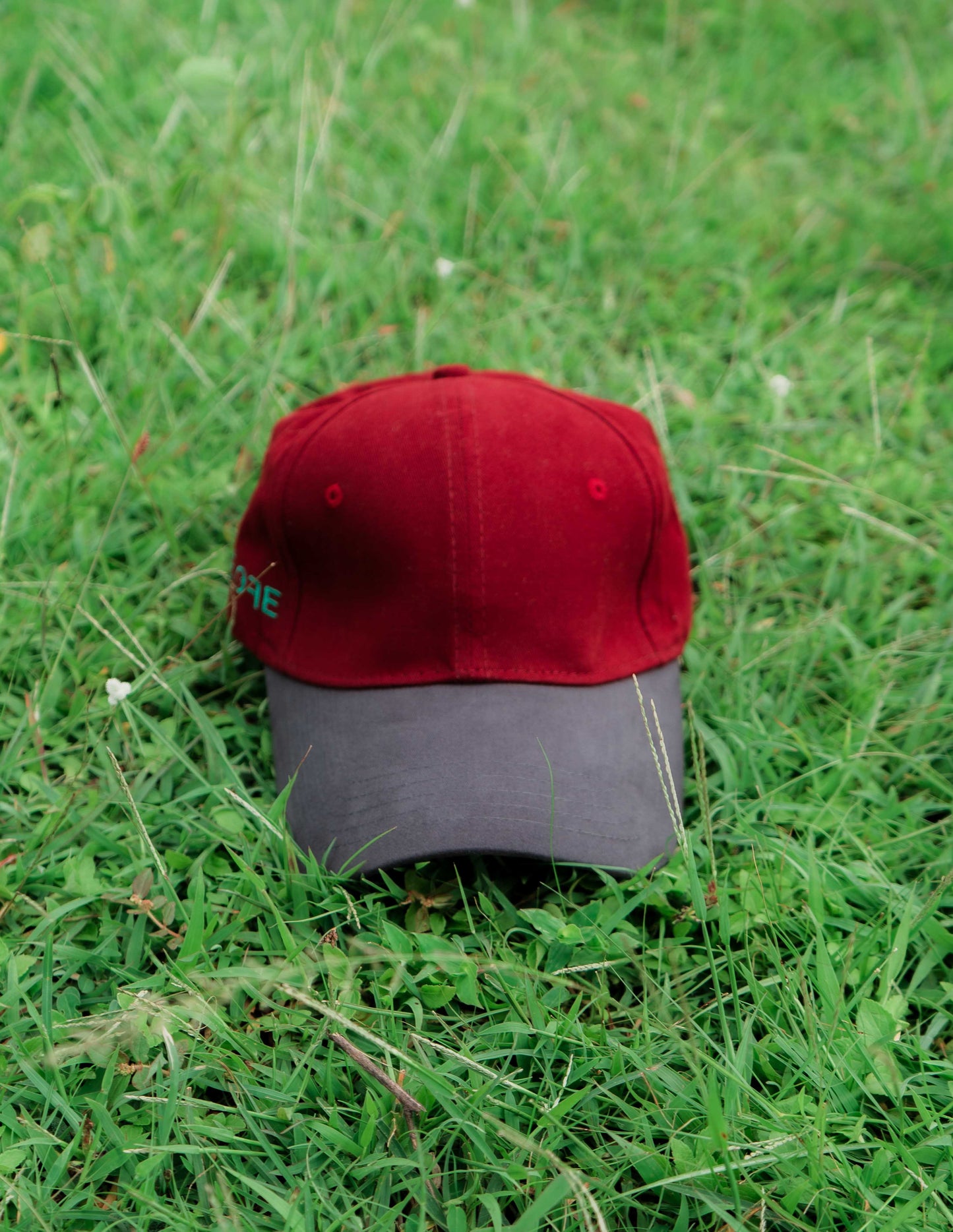 Red & grey ORE OFE baseball cap on grass