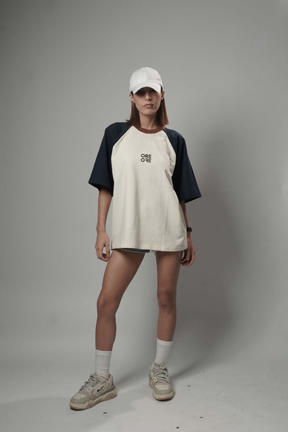 Person wearing a white and navy baseball shirt, shorts, and cap on a gray background