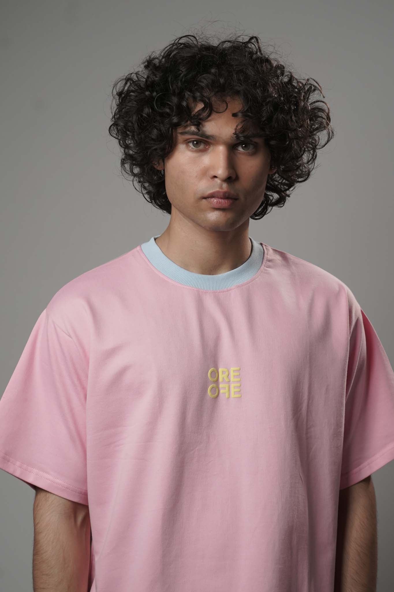 Person wearing a pink t-shirt with a yellow logo on a gray background