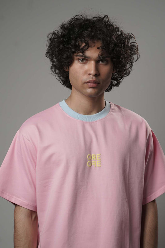Person wearing a pink t-shirt with a yellow logo on a gray background