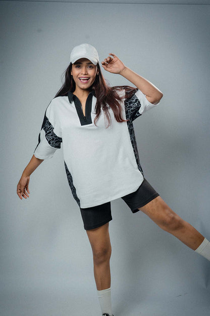 Woman wearing a white and black outfit with a cap on a gray background