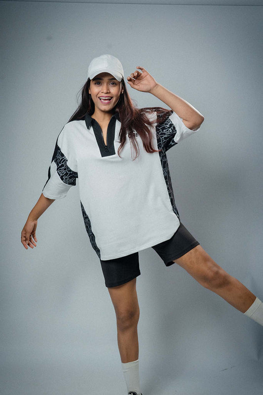 Woman wearing a white and black outfit with a cap on a gray background