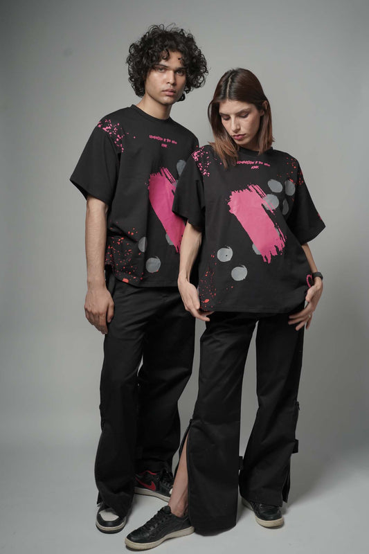 Two people wearing black t-shirts with pink graphic designs on a gray background