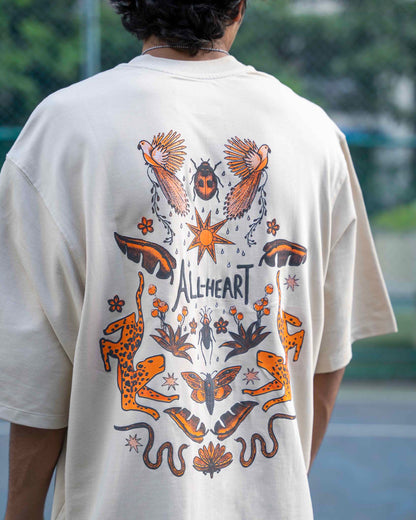 Person wearing a beige t-shirt with a colorful graphic design on the back, featuring animals and the brand 'All heart'.