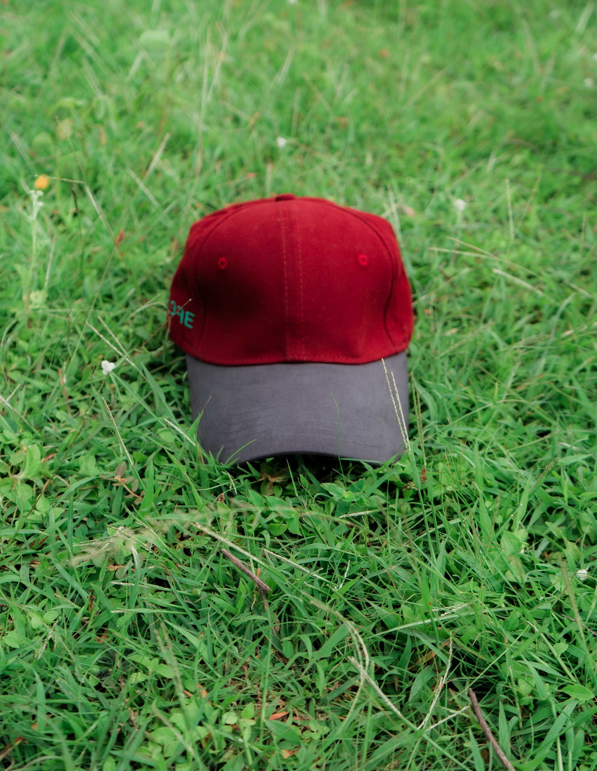 Red & grey ORE OFE baseball cap on grass